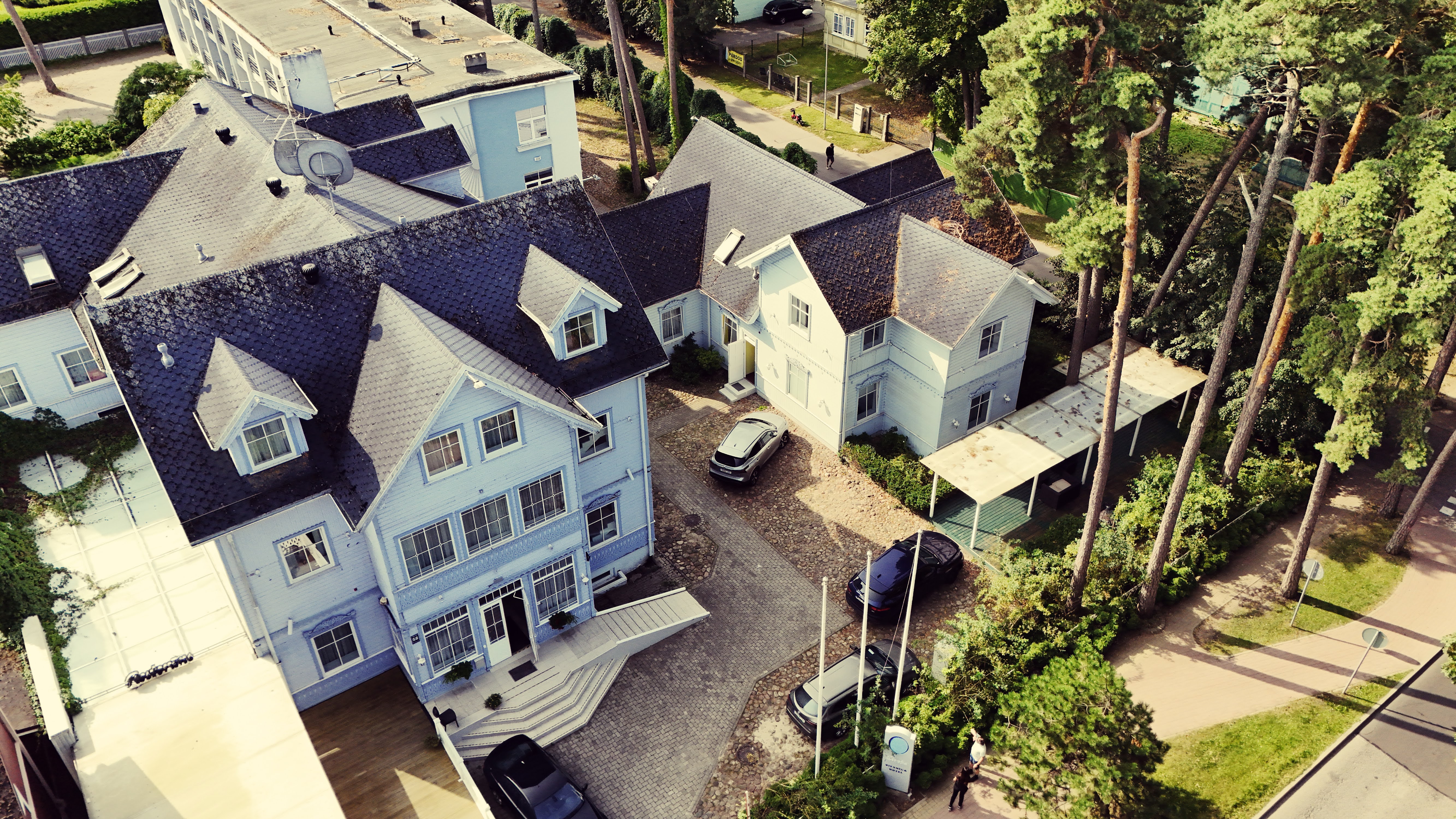 White wooden guest house buildings among pines on Jūras iela
